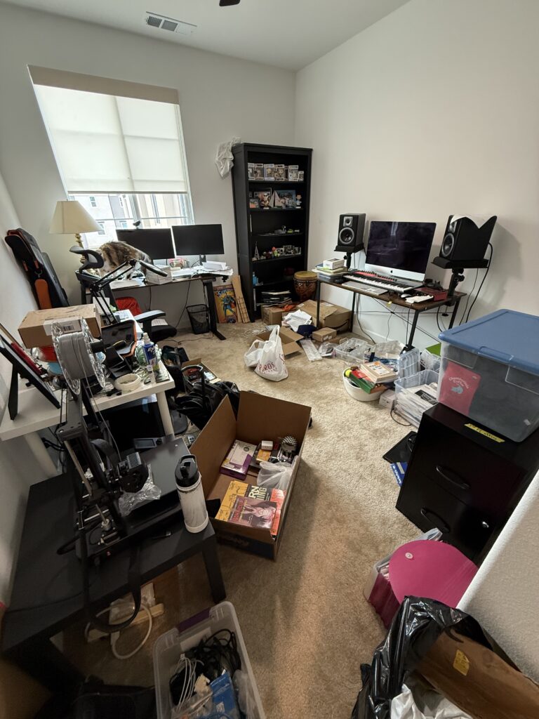 cluttered home office in San Marcos before professional decluttering — boxes, cables, and equipment covering the floor